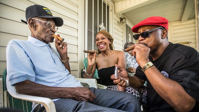 Richard Overton, left, smoked a cigar with a few neighborhood friends Donna Shorts, center, and Martin Wilford in Austin on his 109th birthday, celebrated on a front porch in East Austin with friends and family.