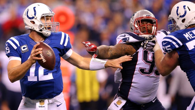 Indianapolis Colts quarterback Andrew Luck (12) drops back to pass as he's pressured by New England Patriots defensive tackle Dominique Easley (99) during second half action of an NFL football game Sunday, Oct. 18, 2015, at Lucas Oil Stadium.