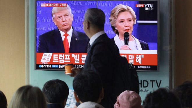 People watch a TV screen showing the live broadcast of the U.S. presidential debate between Democratic presidential nominee Hillary Clinton and Republican presidential nominee Donald Trump, at Seoul Railway Station in Seoul, South Korea, Monday, Oct. 10, 2016. (AP Photo/Ahn Young-joon)