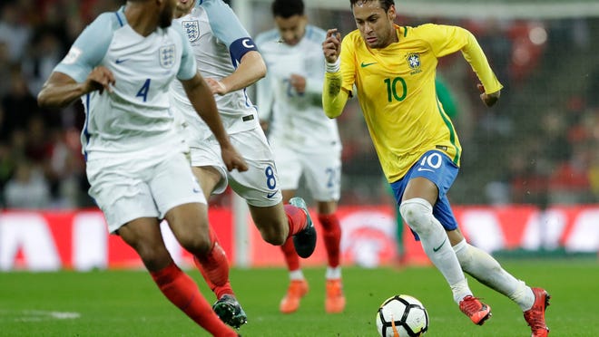 Brazil's Neymar takes the ball forward watched by England's Joe Gomez, left, and England's Eric Dier during the international friendly soccer match between England and Brazil at Wembley stadium in London, Britain, Tuesday, Nov. 14, 2017. (AP Photo/Matt Dunham)
