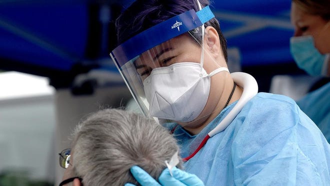 FILE - Michelle Schmitt, a medical assistant at Compass Health Network, removes nasal fluid Friday from a man so it can be tested for the coronavirus that causes COVID-19 at the Compass Health Network.