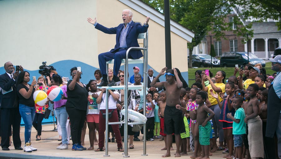 Former Vice President Joe Biden sits in the lifeguard chair and cheers along with the crowd as they reveal the renaming of the pool facility being dedicated in his honor to the Joseph R. Biden Jr. Aquatic Center.