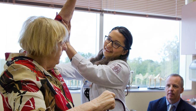 Dr. Elizabeth Midney-Martinez checks for flexibility while tending to one of her patients, Donna H. Fecik on Wednesday, March 11, 2015, as Dr. Mark Farmer supervises in the background. Midney-Martinez is one of 13 members currently participating in the Family Medicine Residency Program at Lee Memorial Hospital.