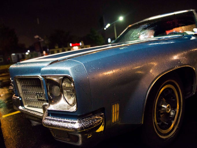 Rain falls on an Oldsmobile parked and displayed on