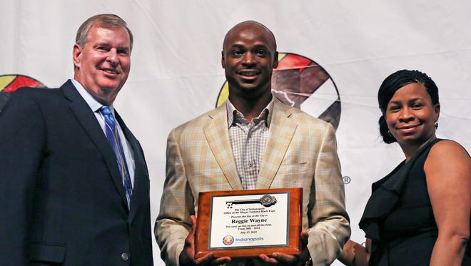 Indianapolis Mayor Greg Ballard (left) presents the Key to the City to former Indianapolis Colts player Reggie Wayne (center) at the Indiana Black Expo Summer Celebration's Corporate Luncheon Friday, July 17, 2015. At right is Tanya Bell, president and CEO of Indiana Black Expo.