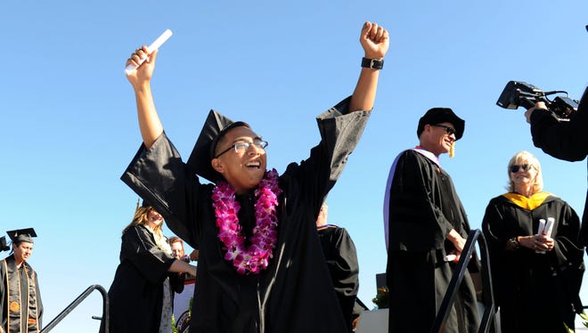 Abraham Morales celebrates after getting his degree certificate at the Ventura College commencement ceremony Friday.