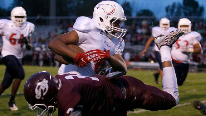 Everett’s D’Andre Taylor avoids a diving tackle attempt by Okemos’ Dalis Williams en route to a touchdown Friday. Taylor scored four times in Everett’s win.