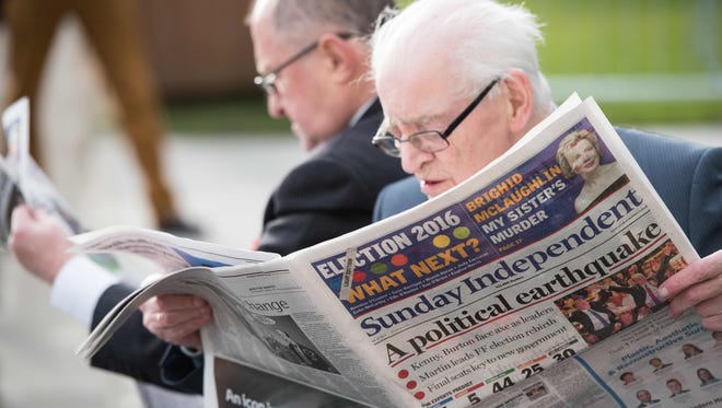 Fianna Fail officials read the morning newspapers as they wait outside the count center in Dublin, Ireland on Sunday.