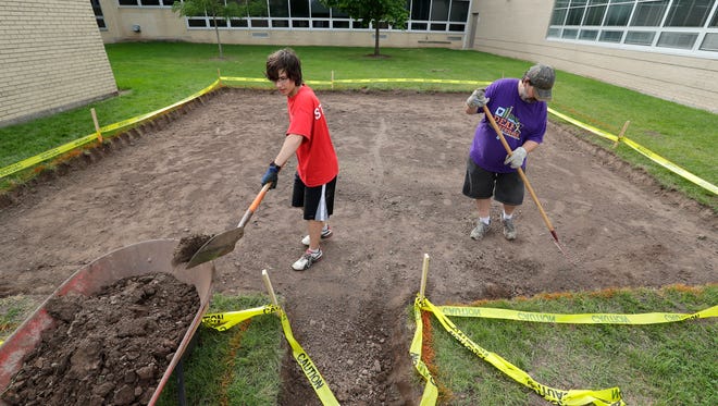 Appleton East High School student Trebor Rusch, 16, prepares the site where he will install a labyrinth at Madison Middle School on Friday, August 26, 2016 in Appleton, Wisconsin. Trebor is installing the labyrinth to complete his Boys Scouts Eagle rank.   At right is Trebor's father Robert Rusch. Trebor needs to dig out eight inches of soil before they can pour concrete for the project.