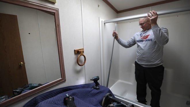 Brad Rudie, an installer with Tundraland, begins the demolition of Norman and Millie Bodway's bathroom as a part of the "Baths for the Brave" campaign Tuesday.