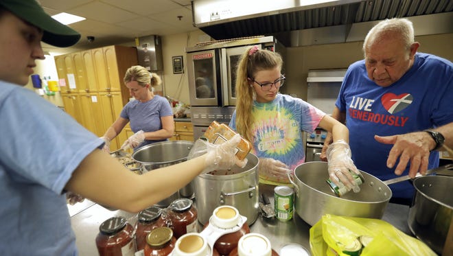 Volunteers Maria Minkey, from left, of Appleton, Stacey Steffens of Combined Locks, Brooke Steffens of Combined Locks and Ralph Young of Little Chute collaborate Tuesday afternoon to make dinner for clients at Homeless Connections, a shelter at 400 N. Division Street in Appleton.