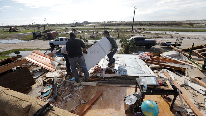 Lupe Tijerina, left, and Andy Guerra, center, and Felix Tijerina, right, work on Aug. 29, 2017 to salvage items from their family home that was destroyed in the wake of Hurricane Harvey in Rockport, Texas. 