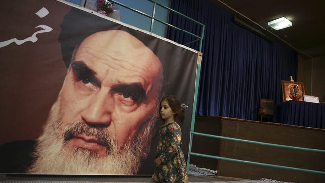 In this Jan. 22, 2019, photo, a girl walks past a poster of Ayatollah Ruhollah Khomeini, at a mosque where he made speeches, in northern Tehran, Iran. The memory of Khomeini, who died in 1989 at the age of 86, looms large over Tehran today. His image is on bank notes and in textbooks in Iran, often as an embodiment of the 1979 Islamic Revolution that swept aside the country’s shah and forever changed the nation.
