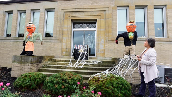 Deb Swartz, clerk at the Bellevue Library, shows the scarecrows that were decorated for the second annual Scarecrow Contest.