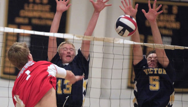 Victor's Jack Broderick, center, and Cam Cummings, right, block a kill by Canandaigua's Sean Steedman.