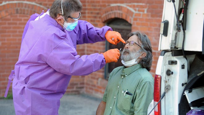 Fallon Ambulance Supervisor Dan Scanlon gives Sandy Sheble-Hall, of Dover, a COVID-19 test at the walk-up test site at the Amazing Things Arts Center in Framingham on Tuesday.