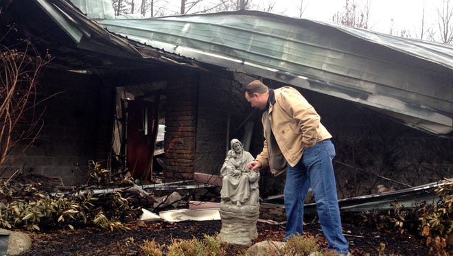 Senior Pastor Kim McCroskey inspects a statue outside the remains of the family life center at Roaring Fork Baptist Church in Gatlinburg on Dec. 6, 2016. The church and the center burned down in wildfires a week earlier.