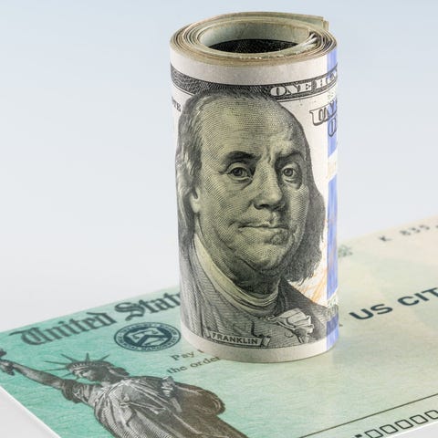 Roll of $100 bills on top of a U.S. Treasury stimu