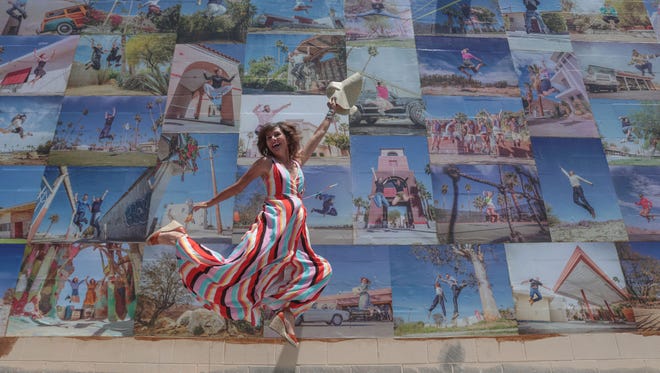 Artist Eyoalha Baker jumps in front of her mural made up of photos of Coachella Valley residents jumping during the unveiling ceremony on Saturday, May 19, 2018 at the Palm Springs Cultural Center, formerly the Camelot in Palm Springs. The piece is titled  "Jump for Joy."