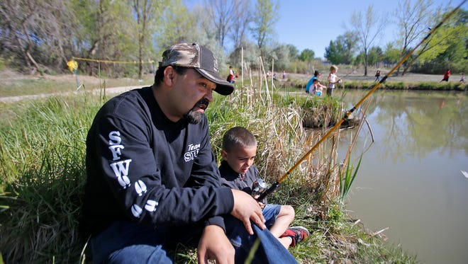Tiger Espinoza, vice president of Sportsmen for Fish and Wildlife's New Mexico chapter, teaches kindergartner Jacobi Cascio how to fish on Friday at Riverside Park in Aztec.