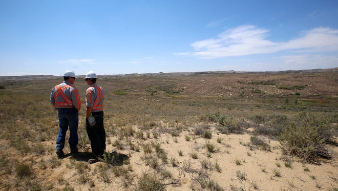 BHP Billiton General Manager Shawn Goeckner, left, and BHP Billiton Superintendent of Drilling and Blasting Josha Kantor examine a portion of the Navajo Mine's Chinde Reclamation area in Fruitland on May 26.