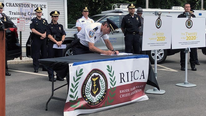 Col. Hugh T. Clements Jr., chief of the Providence Police Department, signs a list of 20 reform promises at an event in Cranston on Thursday.