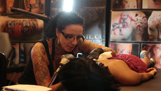 Artist Britta Christiansen, from San Clemente, CA, works on a tattoo during the first annual Palm Trees and Tattoos tattoo convention held at the Hard Rock Hotel on Saturday, July 12, 2014 in Palm Springs.