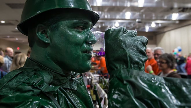 Costumes mixed with beer and wine tasting were part of the 3rd annual charity Casks & Casket Homebrew that took place at the Oshkosh Convention Center November 1, 2014. Jeff Schmoker dressed as a plastic army figure samples beer.