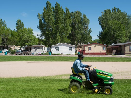 A man cuts the grass at Poudre Valley Mobile Home Park