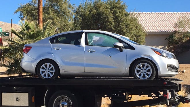 A car is removed from the scene with what appears to be bullet holes.