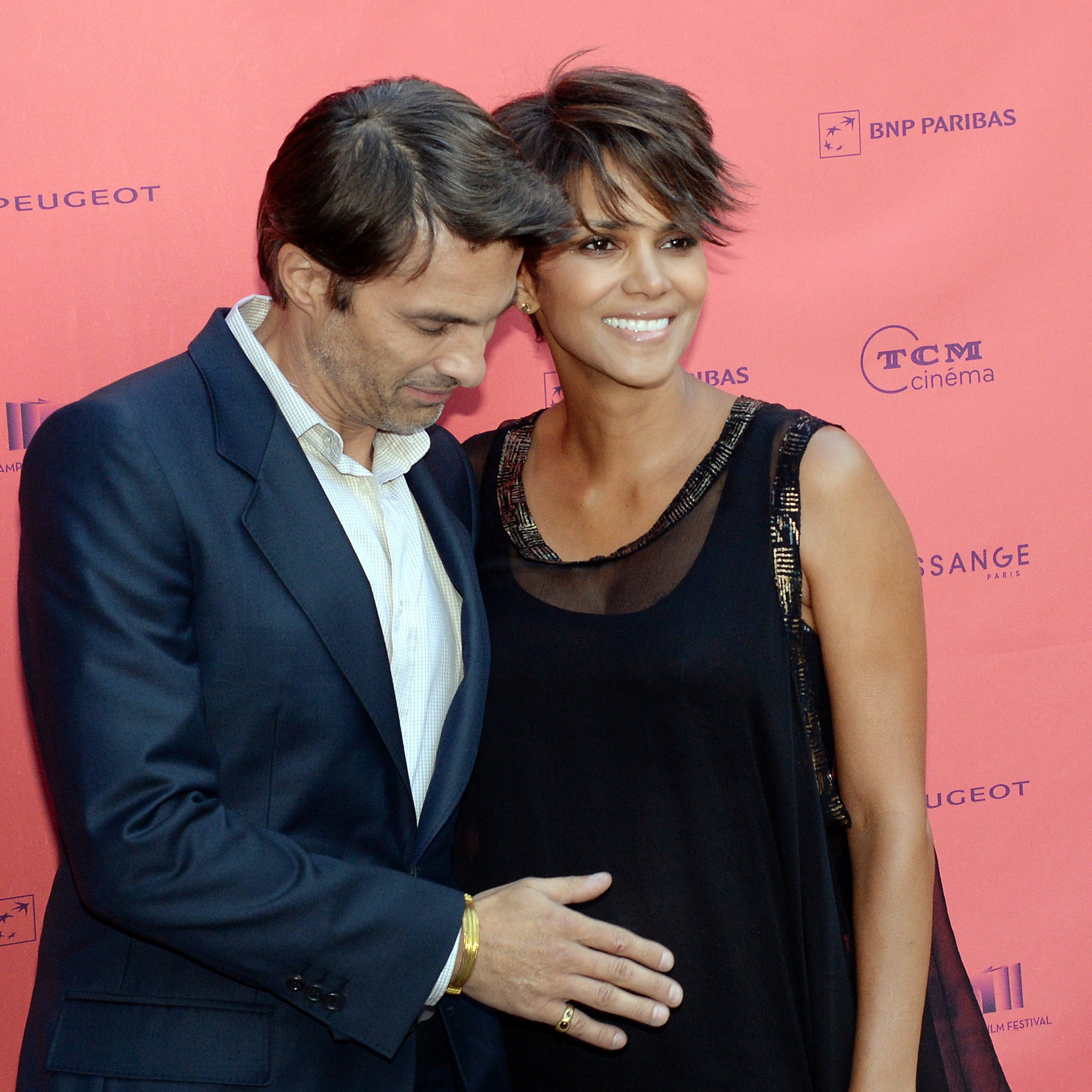 French actor Olivier Martinez touches his baby bump with fiancee Halle Berry on June 13, 2013, upon their arrival for the Champs-Elysees Film Festival in Paris.  The two would go on marry and have a son.  However they would eventually file for divorce - the third marriage for Berry.