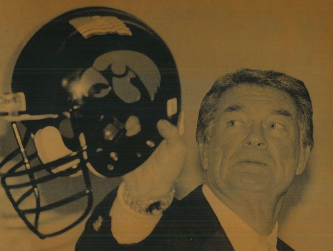 Coach Hayden Fry holds an Iowa helmet with an American