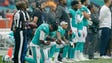 Miami Dolphins players kneel down during the national