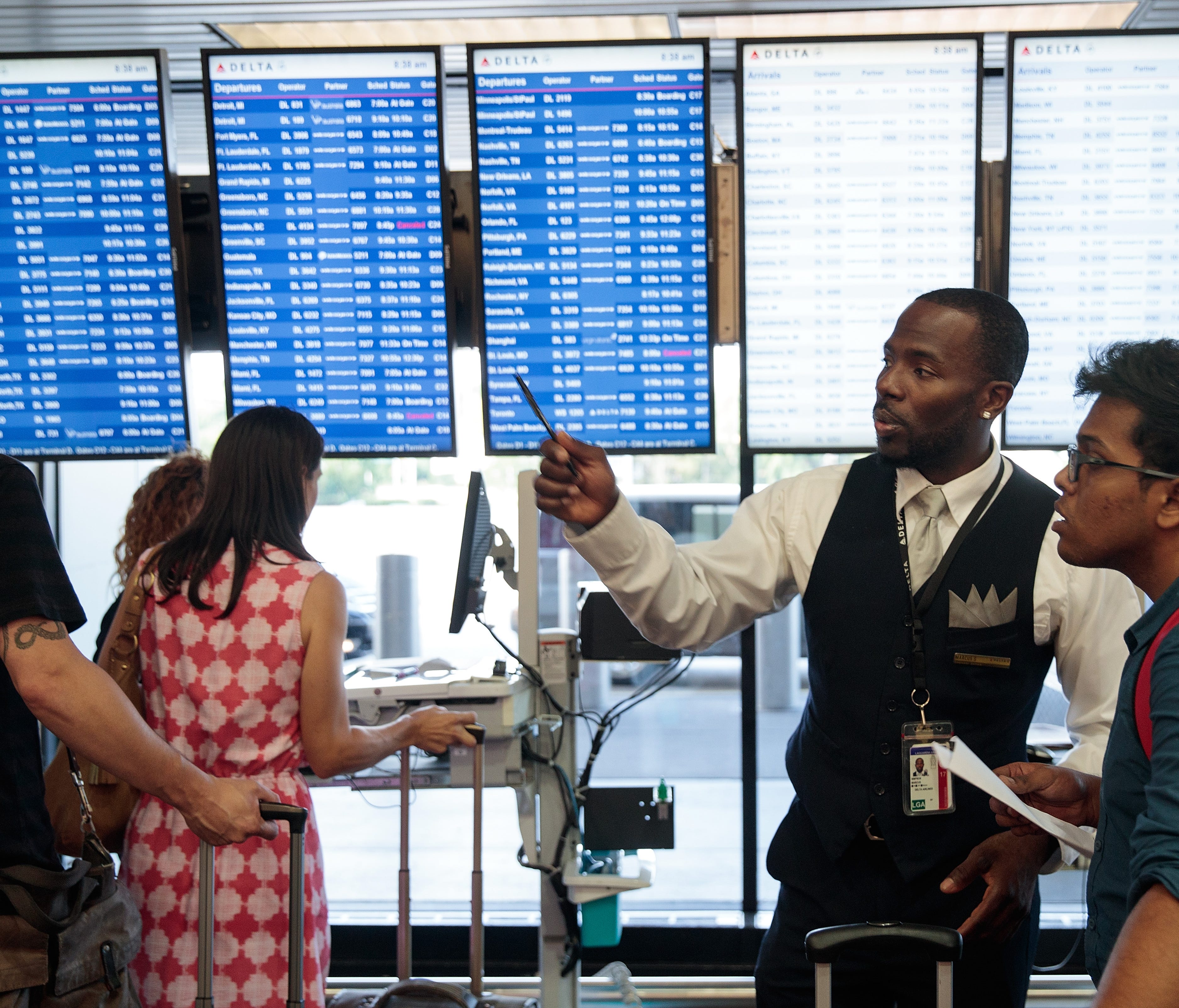 A Delta employee helps travelers at LaGuardia Airport on Aug. 8, 2016.