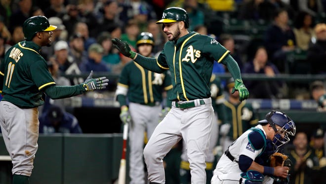 Oakland Athletics' Matt Joyce (center) shares congratulations at home on his two-run home run with Rajai Davis as Seattle Mariners catcher Carlos Ruiz looks down during the ninth inning of Tuesday's baseball game.