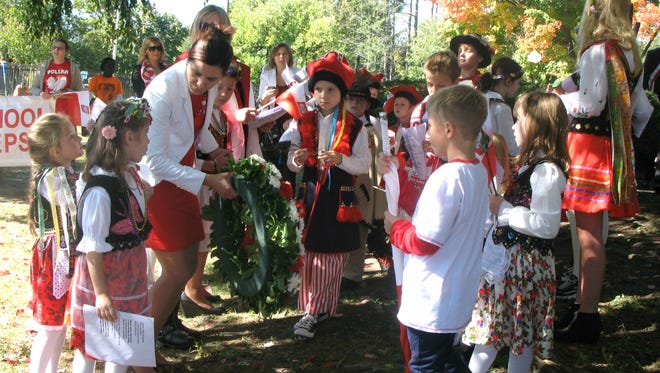 Beata Mroczek, vice president of the School of Polish Language at St. Joseph’s Church, helps students place the ceremonial wreath on the Pulaski Park monument on Sunday.