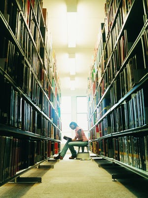 Female University Student Reading a Book in a Library