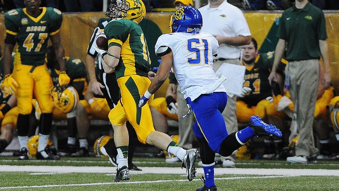 NDSU's R.J. Urzendowski (16) hauls in a pass in front of SDSU's J.T. Hassell (51) during the second half of an FCS playoff game on Saturday, Dec. 6, 2014, in Fargo, N.D. The Bison defeated the Jackrabbits 27 to 24.