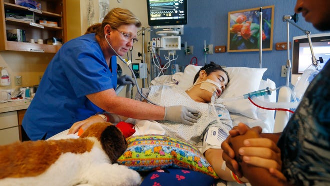 Angela Michael, a registered nurse at Mercy Hospital, listens to Bradley Quigley's heart beat as his stepfather Jose Toto holds his hand on Wednesday, Aug. 31, 2016. Bradley, who is from Siloam Springs, Arkansas, is at Mercy recovering from a hit and run accident.