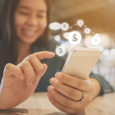 Woman holding a smartphone with dollar sign icons 