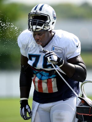 Titans tackle Byron Bell (76) takes a drink during practice Tuesday.