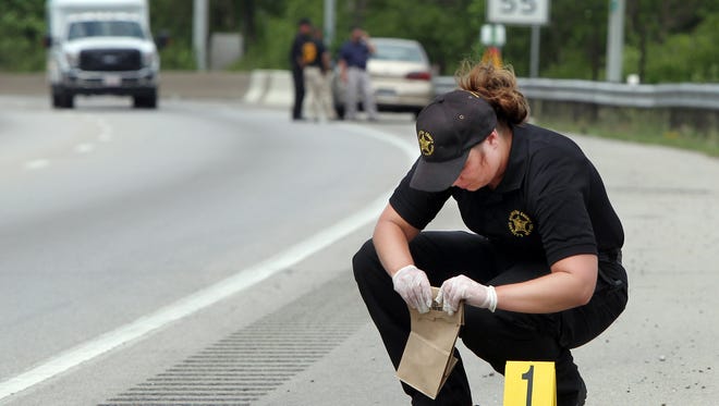 Hamilton County Sheriff's Department evidence technician Heather Sanderson collects evidence and evidence markers along the shoulder of northbound I-75 near Davis Street.