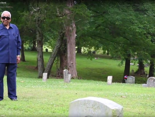 Charles Morris stands at the unmarked grave of his