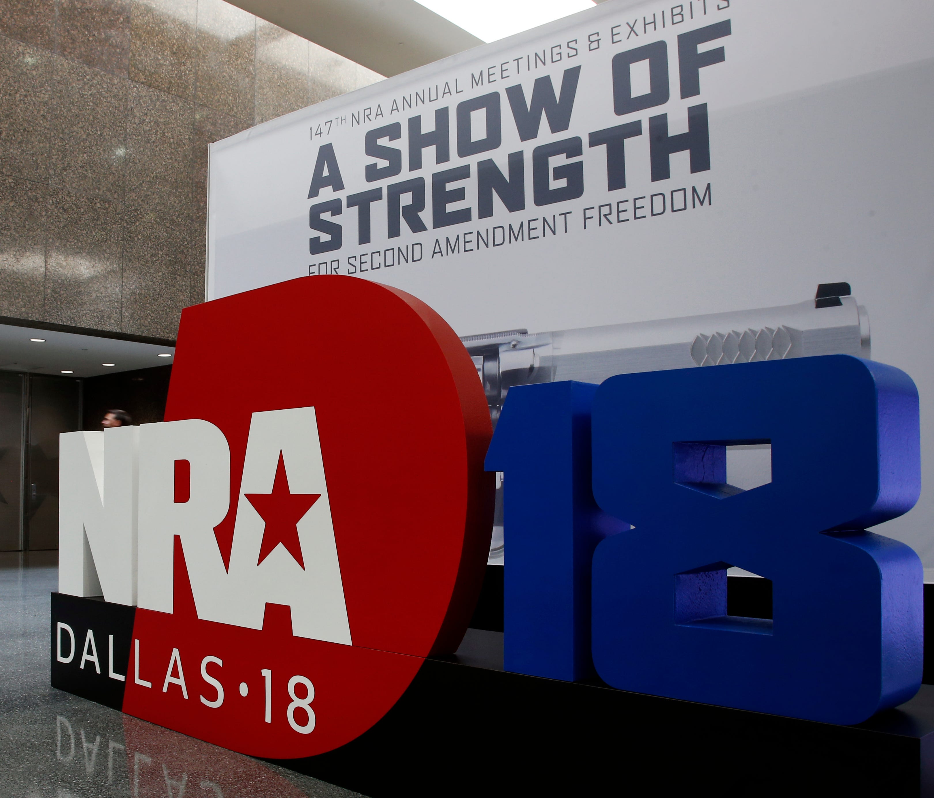 People walk by NRA convention signage in the Kay Bailey Hutchison Convention Center in Dallas,