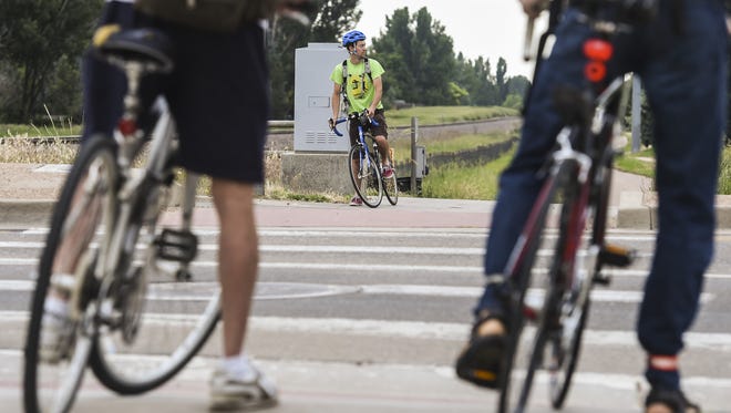 Alex Davis waits to cross Drake Road on the Power Trail to stop at a Bike to Work Day station Wednesday, June 24, 2015 in Fort Collins, CO.
