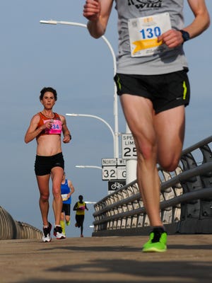 Erin Moeller, left, of Mount Vernon, Iowa, hurries over the De Pere bridge on her way to winning the women’s race in the Cellcom Green Bay Marathon on Sunday, May 17, 2015.