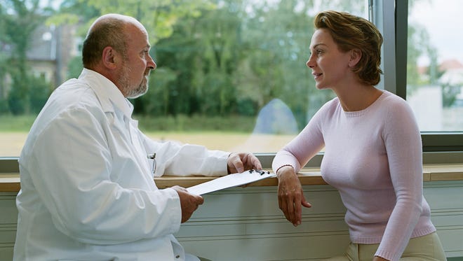 Male doctor sitting with female patient by window