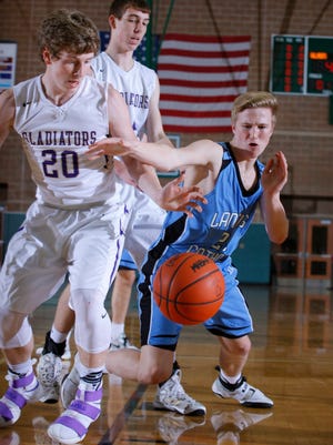 Fowlerville's Cam Brigham, left, and Lansing Catholic's Matthew Plaehn vie for the ball during their district game Monday, March 6, 2017, in East Lansing, Mich. Fowlerville won 66-52.