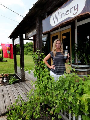 Candy Wence holds a bottle of wine in front of The Big Creek Winery Tasting Room, in Christiana, Tenn. on Friday, July 20, 2018.