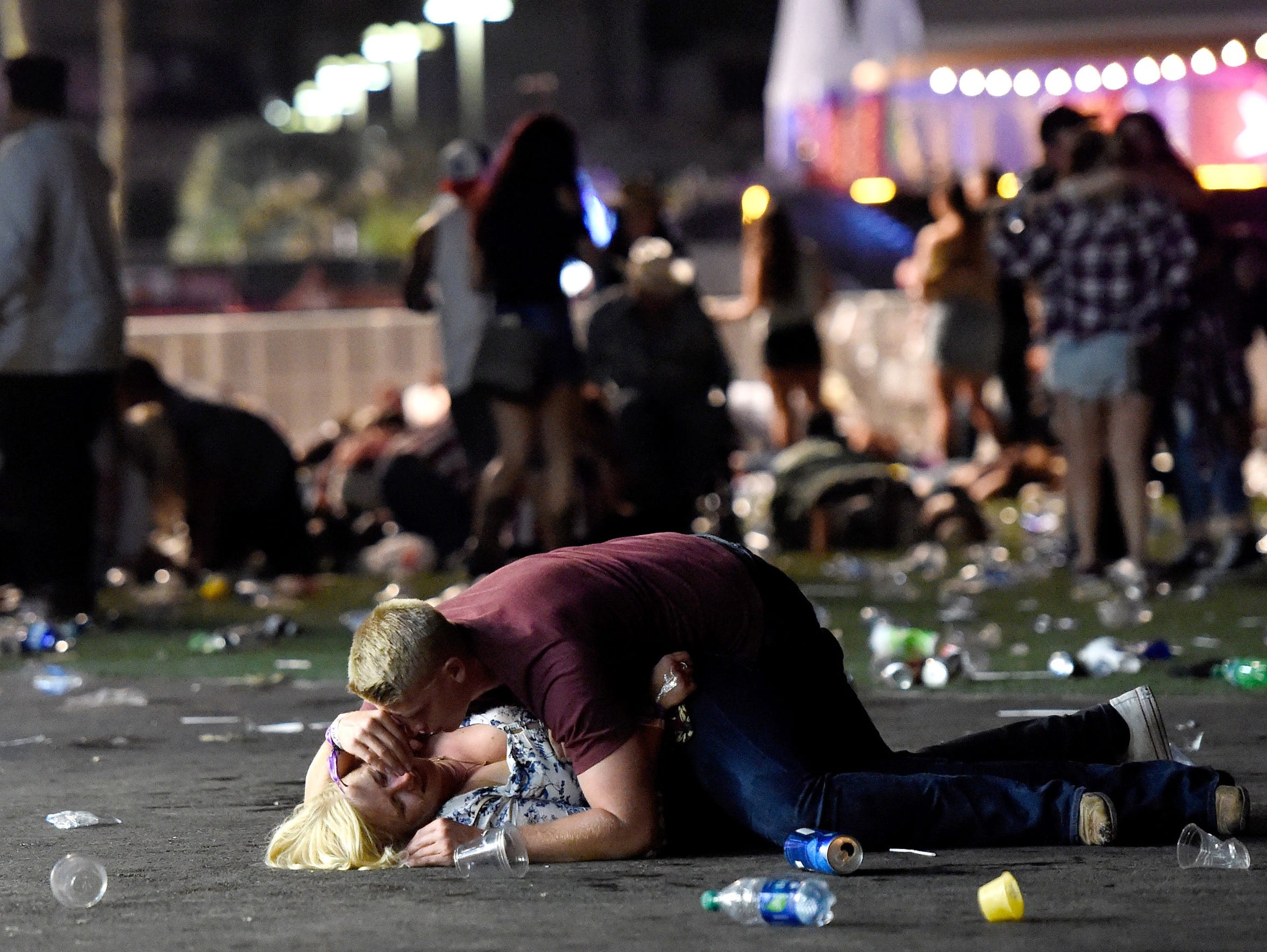 A man lays on top of a woman as others flee the Route 91 Harvest country-music festival after a shooter opened fire on the festivals grounds on Oct. 1, 2017.